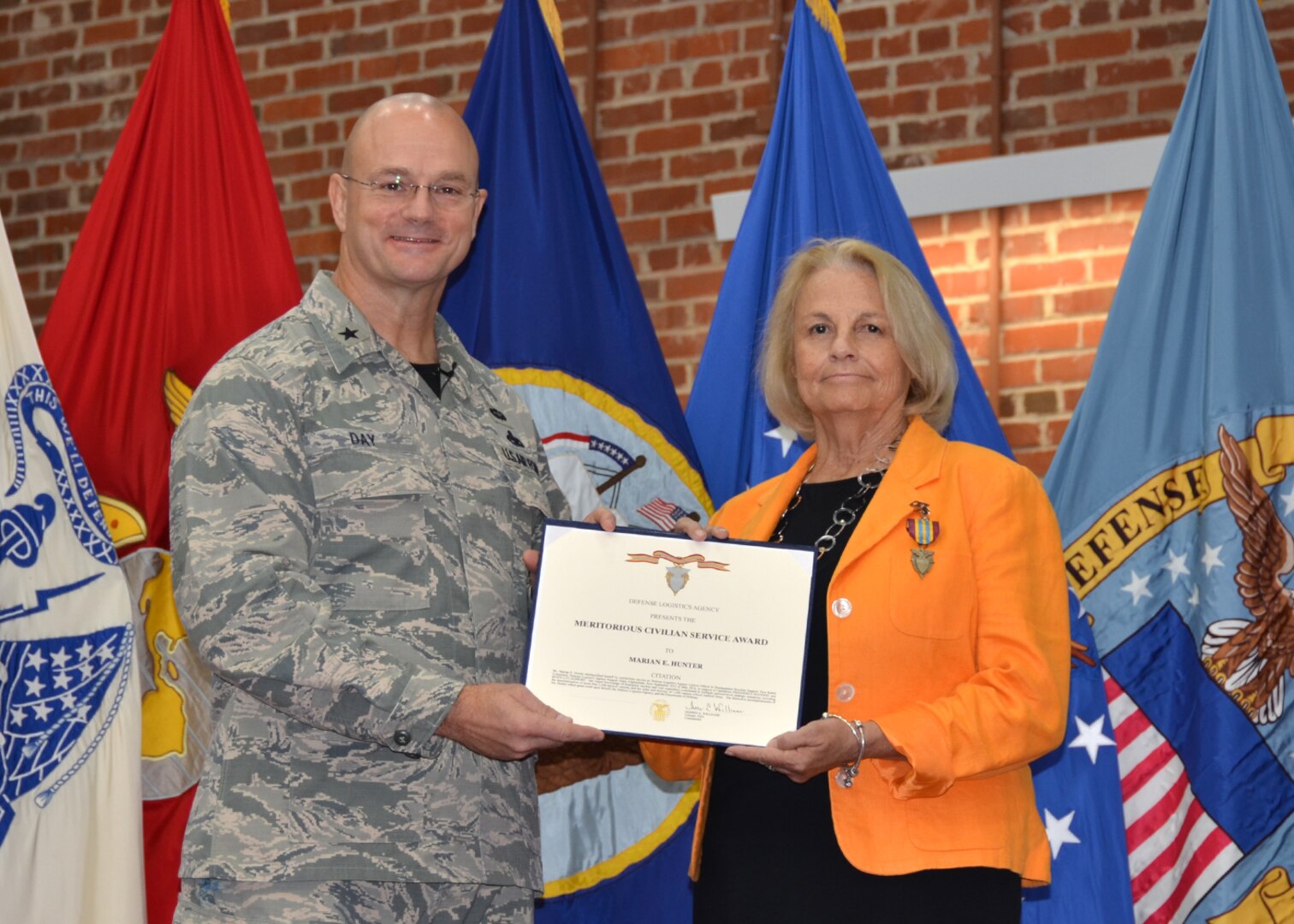Defense Logistics Agency Aviation Commander Air Force Brig. Gen. Allan Day presents Marian Hunter, weapons systems support manager, DLA Aviation Customer Operations Directorate, Mapping Division, with the Meritorious Civilian Service Award during his town hall held at the Lotts Center on Defense Supply Center Richmond, Virginia, July 15, 2016. 
