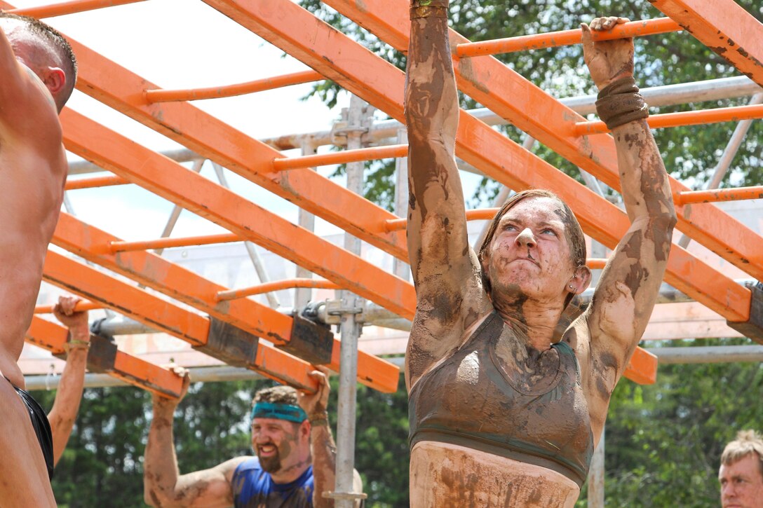 HUGO, Minn.-- Participants of the 2016 Twin Cities Tough Mudder swing through the Funky Monkey, an obstacle where angled monkey bars meet a trapeze six feet over a pool of mud in Hugo, Minnesota July16. Throughout the 10-12 mile obstacle course, racers are faced with over 20 different muddy challenges. Army Reserve Soldiers from local units provide support for the two day event. (U.S. Army photo by Spc. Claudia Rocha)