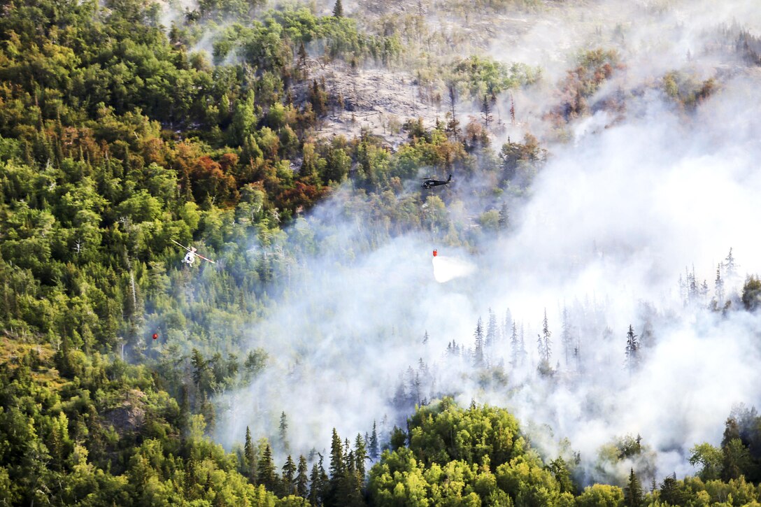 An Army UH-60 Black Hawk helicopter and a civilian helicopter drop water while supporting response efforts to the McHugh Creek Fire near Anchorage, Alaska, July 20, 2016. Army National Guard photo by Staff Sgt. Balinda O’Neal Dresel