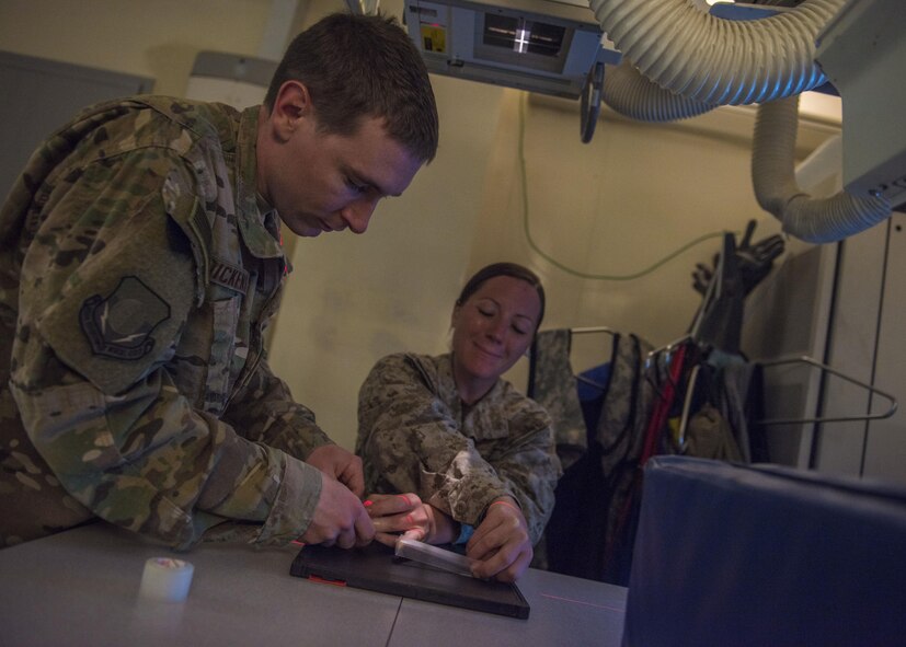 Staff Sgt. Keenan Dickens, diagnostic imaging technician, repositions a patients hand for an x-ray, Bagram Airfield, Afghanistan, July 20, 2016. X-ray imaging helps health care providers pin point injury origin and establish treatment for patients. The radiology department performs various types of imaging such as radiography, computed tomography and ultrasound. After being examined by the radiologist, the imagery is used by health care providers to manage care for patients. (U.S. Air Force photo by Senior Airman Justyn M. Freeman)