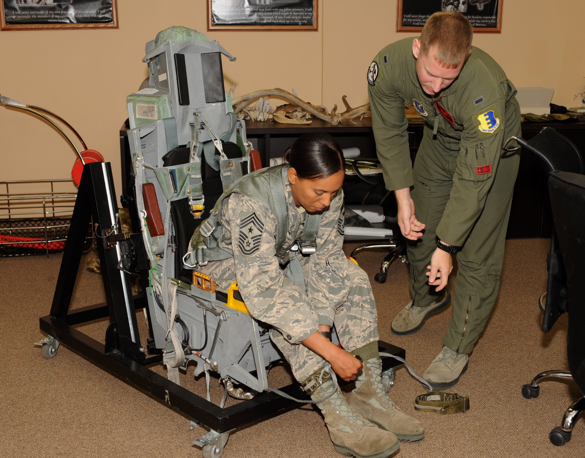Chief Master Sgt. Sonia Lee, the command chief of the 28th Bomb Wing, straps into a B-1 bomber training seat as part of pre-flight training with 1st Lt. Matthew Herbstreth, 34th Bomb Squadron pilot, at Ellsworth Air Force Base, S.D., July 13, 2016. During the training, Lee learned about aircraft safety procedures, how to properly wear the equipment and participated in parachute training. (U.S. Air Force photo by Airman 1st Class Denise M. Nevins)