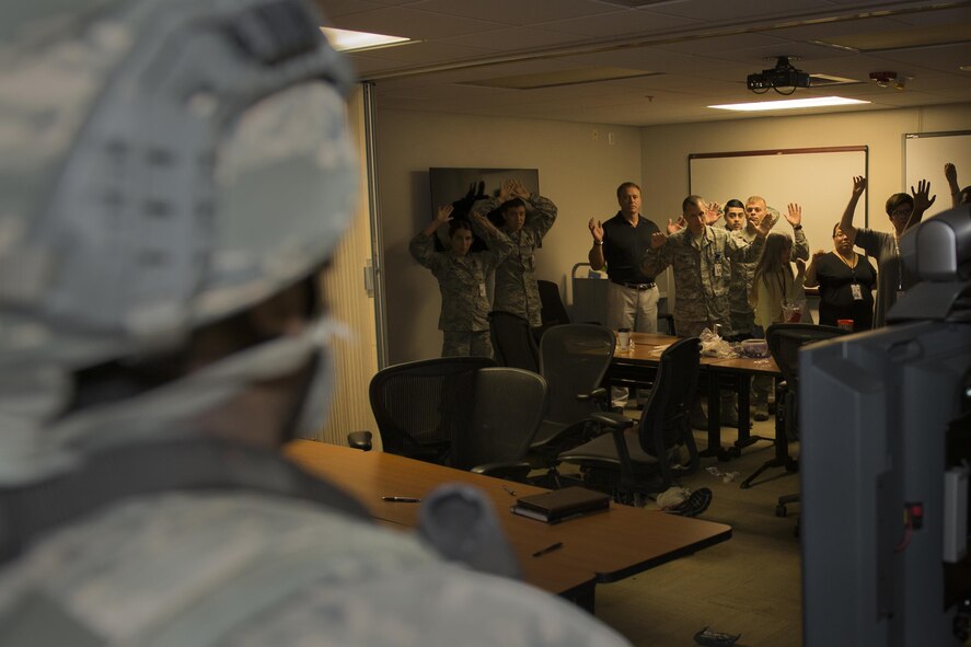 Members from the 23d Medical Group show that they are unarmed as a member of the 23d Security Forces Squadron enters the room during an active-shooter exercise, July 20, 2016, at Moody Air Force Base, Ga. A few members were directed to panic to simulate the stress of a real-world situation. (U.S. Air Force photo by Airman Daniel Snider)