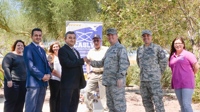 Ercan Aydogdu, Coral Academy of Science Las Vegas (CASLV) executive director and CASLV representatives, receive building keys from Col. William Norton, 99th Mission Support Group commander, Chief Master Sgt. William Arcuri, 99th MSG command chief, July 1, 2016. The school transitioned to CASLV over the summer and will begin the academic school year Aug. 22. (U.S. Air Force photo by Senior Airman Kristin High/Released)