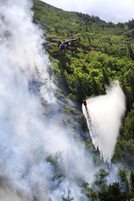 An Army UH-60 Black Hawk helicopter drops water from a bucket firefighting system while assisting in the response to the McHugh Creek Fire near Anchorage, Alaska, July 20, 2016. Army National Guard photo by Staff Sgt. Balinda O’Neal Dresel
