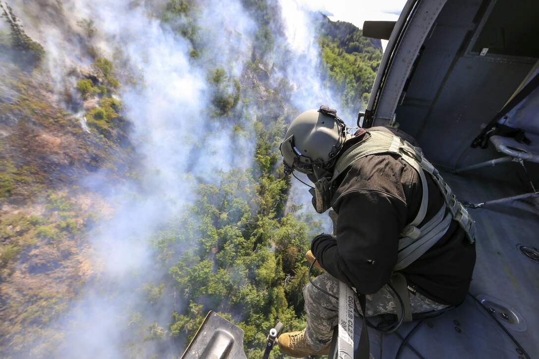 Army Staff Sgt. Steven Elliot looks out the side door of a UH-60 Black Hawk helicopter while assisting in the response to the McHugh Creek Fire near Anchorage, Alaska, July 20, 2016. Elliot is a crew chief assigned to the Alaska Army National Guard’s Company A, 1st Battalion, 207th Aviation Regiment. Army National Guard photo by Staff Sgt. Balinda O’Neal Dresel