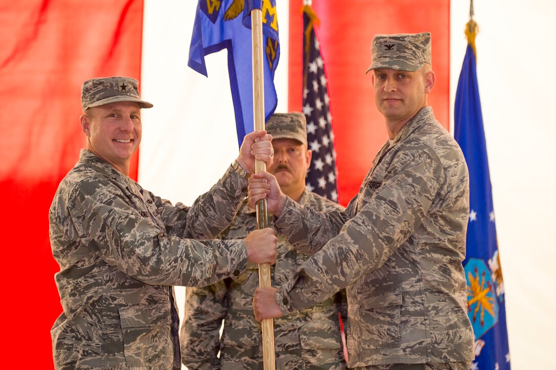 Brig. Gen. Carl Schaefer (left), 412th Test Wing commander, hands the 412th Maintenance Group guidon to the group's new commander, Col. Stephen Grotjohn July 13. (U.S. Air Force photo by Ethan Wagner)