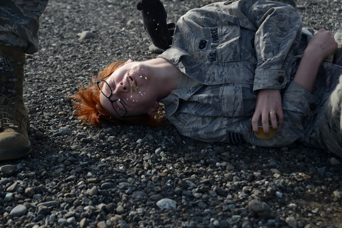 Senior Airman Katrina Kappele, 673d Contracting Squadron specialist, simulates vomiting due to a notional internal injury during Mission Assurance Exercise 16-7 at Joint Base Elmendorf-Richardson, Alaska, July 15, 2016. JBER simulated an aircraft crash to test the base’s ability to operate, coordinate and recover in an efficient and timely manner. (U.S. Air Force photo by Airman 1st Class Christopher R. Morales)