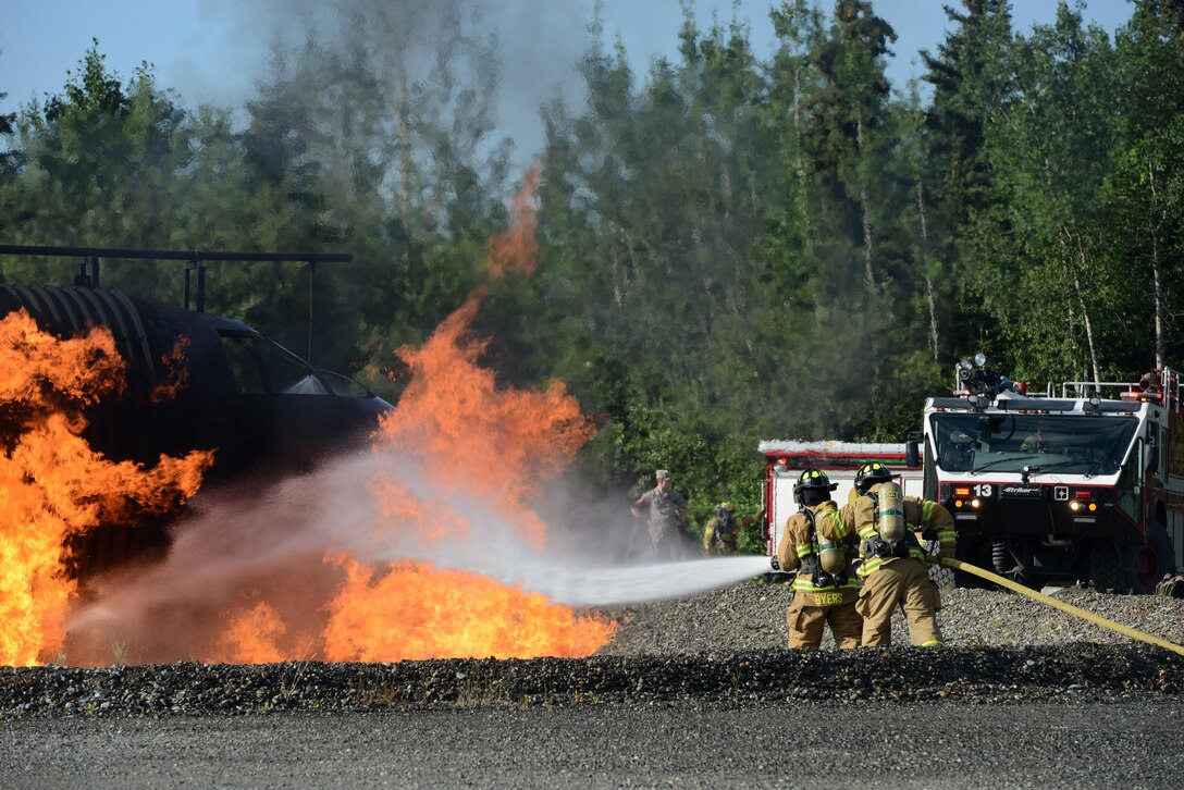 673d Civil Engineer Squadron firefighters extinguish a fire caused by a notional aircraft crash during Mission Assurance Exercise 16-7 at Joint Base Elmendorf-Richardson, Alaska, July 15, 2016. JBER simulated crash to test the base’s ability to operate, coordinate and recover in an efficient and timely manner. (U.S. Air Force photo by Airman 1st Class Christopher R. Morales)