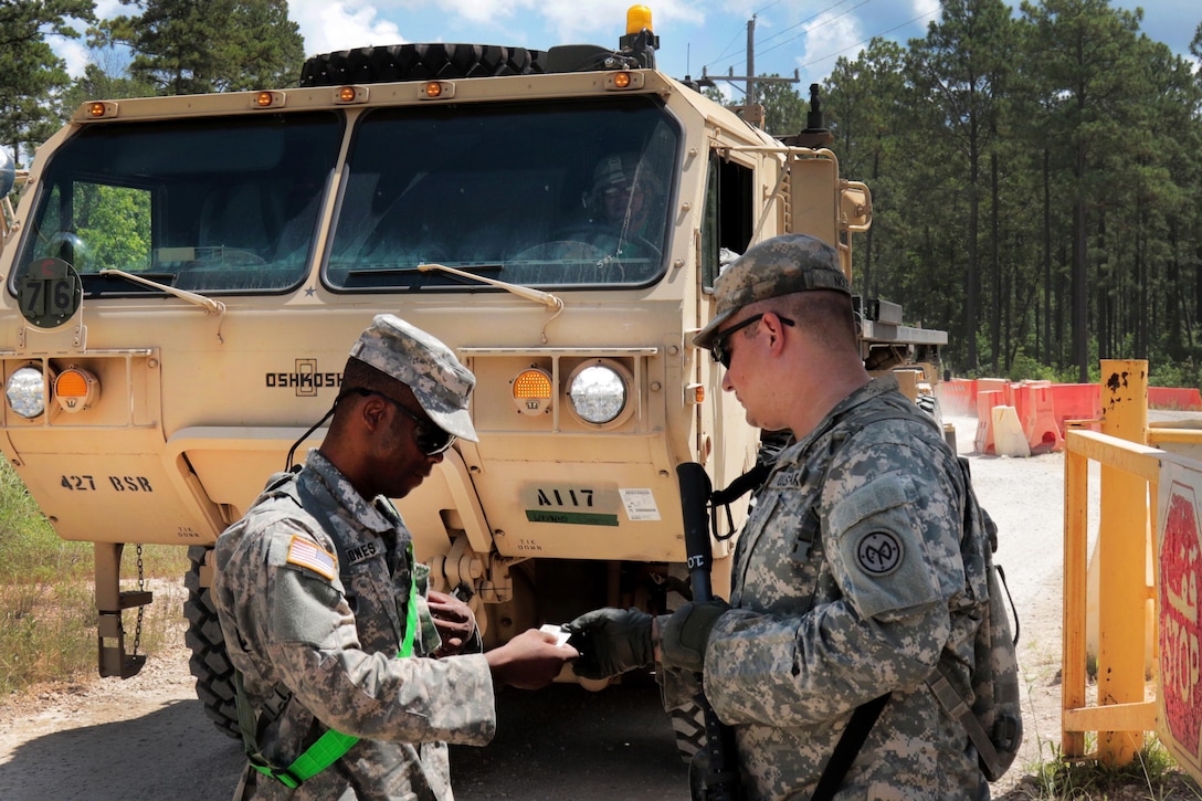 Army Spc. Nole, right, checks identification of a soldier at Forward Operating Base Warrior at Fort Polk, La., July 15, 2016. Army National Guard photo by Sgt. Michael Davis