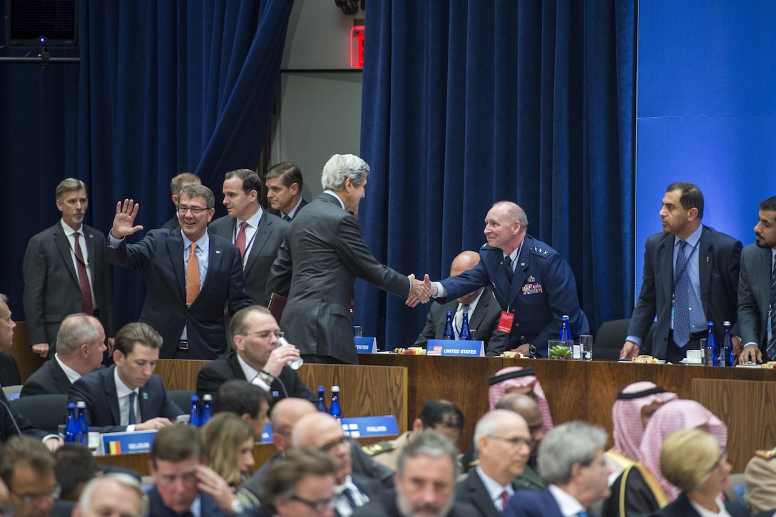 Defense Secretary Ash Carter waves and Secretary of State John Kerry shakes hands as they enter the first meeting of diplomatic, defense and civilian leaders involved in the coalition to counter the Islamic State of Iraq and the Levant in Washington, D.C., July 21, 2016. Carter and Kerry provided remarks at the event, which followed a counter-ISIL meeting the day before with defense ministers and senior leaders at Joint Base Andrews in Maryland. DoD photo by Air Force Tech. Sgt. Brigitte N. Brantley
