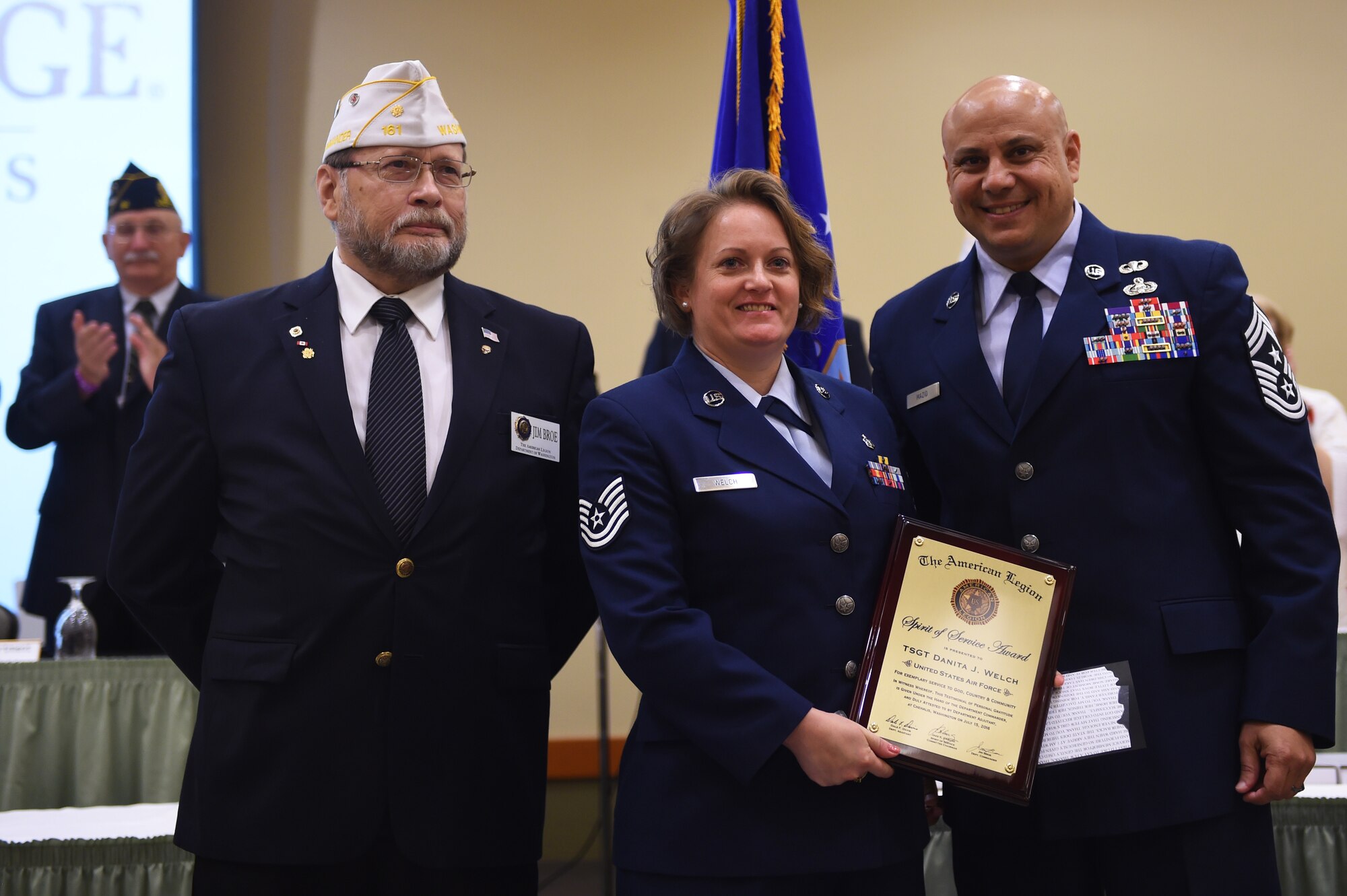 Jim Broe (left), American Legion representative, and Chief Master Sgt. Tiko Mazid (right), 62nd Airlift Wing command chief, present Tech. Sgt. Danita Welch, 62nd Medical Squadron health services manager, is presented with the American Legion Spirit of Service Award in Centralia, Wash., July 15, 2016. Welch, who has served for more than 20 years, was recognized for her service to others by the American Legion for her dedication as a foster parent to more than 50 children. (U.S. Air Force photo/Staff Sgt. Naomi Shipley) 
