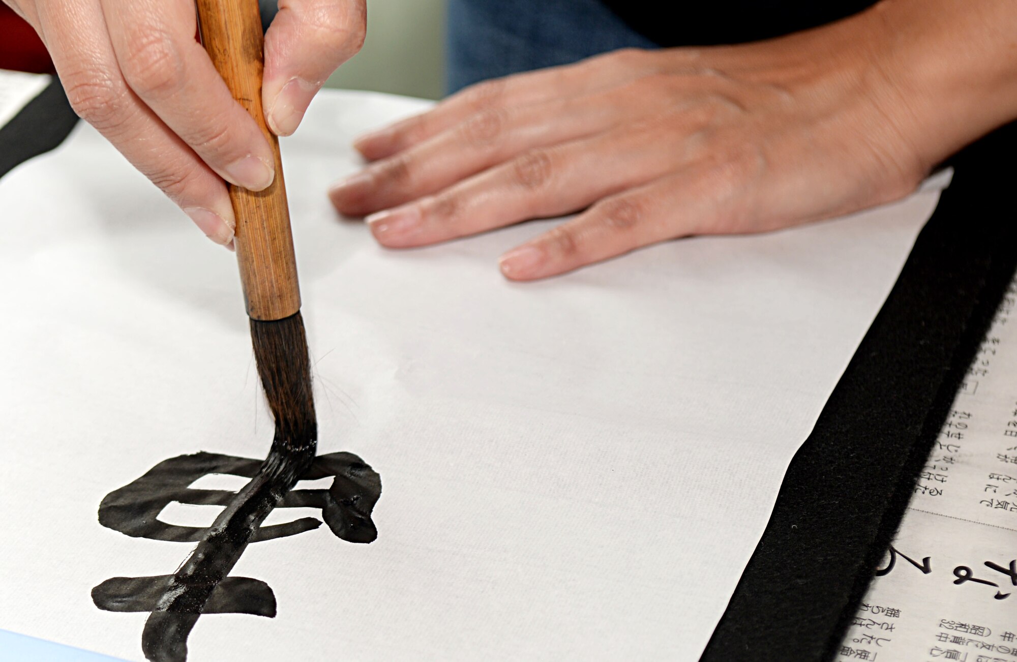 Team Mildenhall members paint Japanese symbols during the Diversity Day celebration July 15, 2016, on RAF Mildenhall, England. Diversity Day is an event held to celebrate different cultures and traditions across the world. (U.S. Air Force photo by Airman 1st Class Tenley Long)