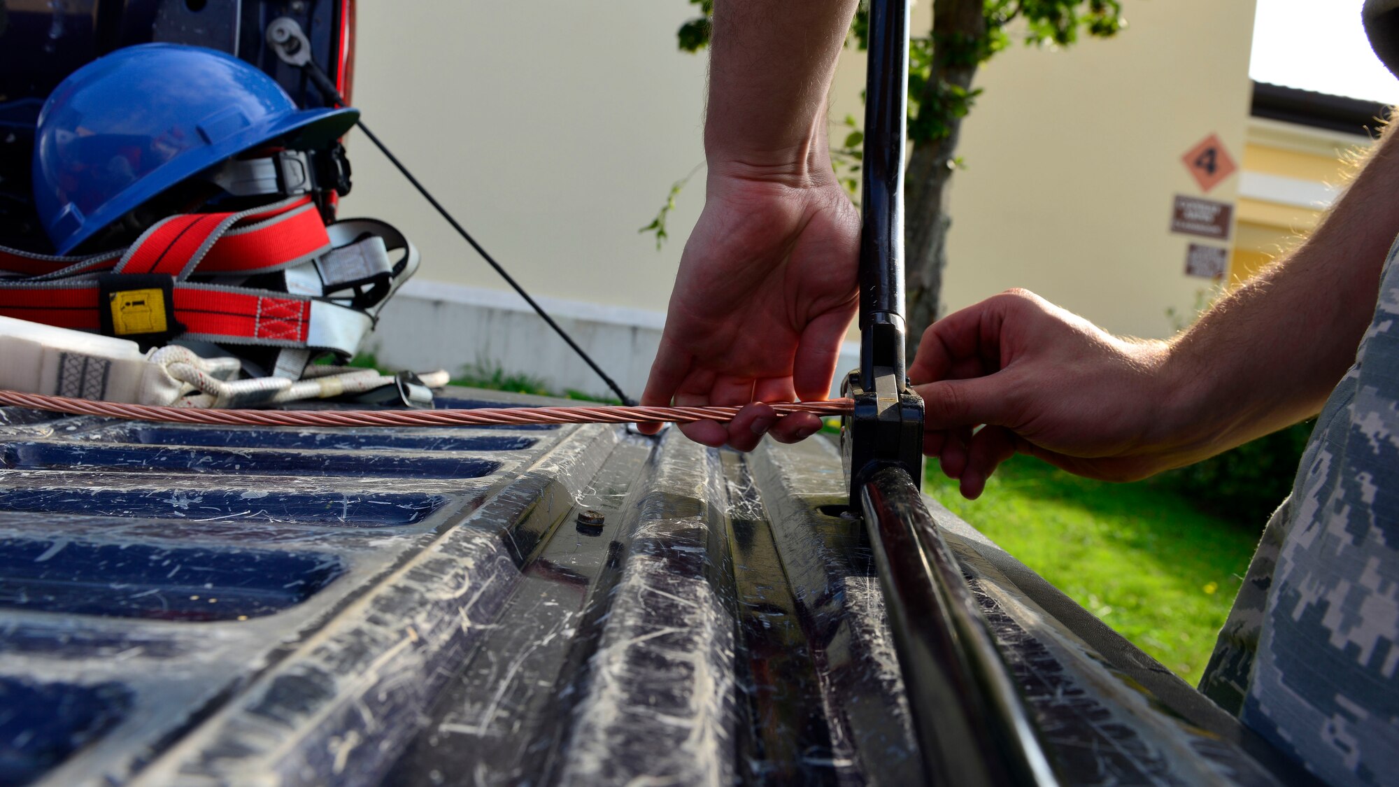 Staff Sgt. Justin Trivett, 31st Civil Engineer Squadron electrical systems journeyman, clamps a connection-end-piece onto copper wire, July 20, 2016, at Aviano Air Base, Italy. The copper wire is connected to a lightning rod to direct the lightning’s electrical currents to the ground. (U.S. Air Force photo by Airman 1st Class Cary Smith/Released)