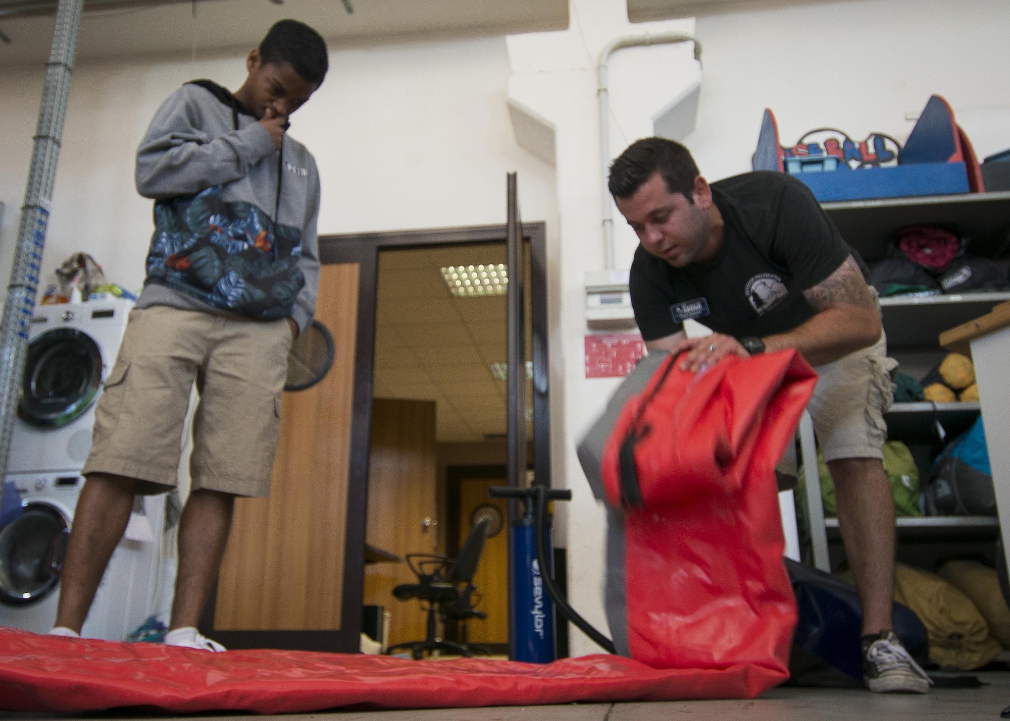Todd Spencer, 31st Force Support Squadron Outdoor Recreational equipment maintenance professional, (right), rolls out an inflatable kayak for a customer July 20, 2016, at Aviano Air Base, Italy. Outdoor Recreation instruct customers on proper use of the equipment, before renting it out. (U.S. Air Force photo by Airman 1st Class Cory W. Bush/Released)