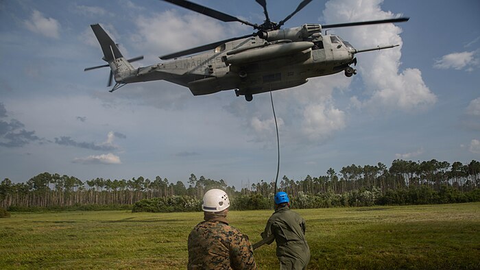 Marine instructors with Expeditionary Operations Training Group stabilize a rope before Marines rappel out of a CH-53E Super Stallion helicopter during elevator drills at Landing Zone Kingfisher, Marine Corps Base Camp Lejeune, N.C., July 13, 2016. Throughout the week, Marine students were taught the essentials of fast roping and the proper procedures to take when conducting training.