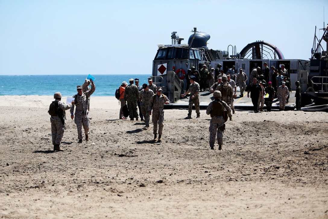 U.S. Marines with Landing Support Company, 1st Transportation Support Battalion, 1st Marine Logistics Group guide distinguished visitors off of a landing craft, air cushion during PACOM Amphibious Leaders Symposium – 16 aboard Camp Pendleton, Calif., July 13, 2016. Several 1st MLG units and Beachmaster Unit 1, Naval Beach Group 1 facilitated the offload of equipment and personnel during the symposium’s beach landing operations demonstration. (U.S. Marine Corps photo by Sgt. Carson Gramley/released)