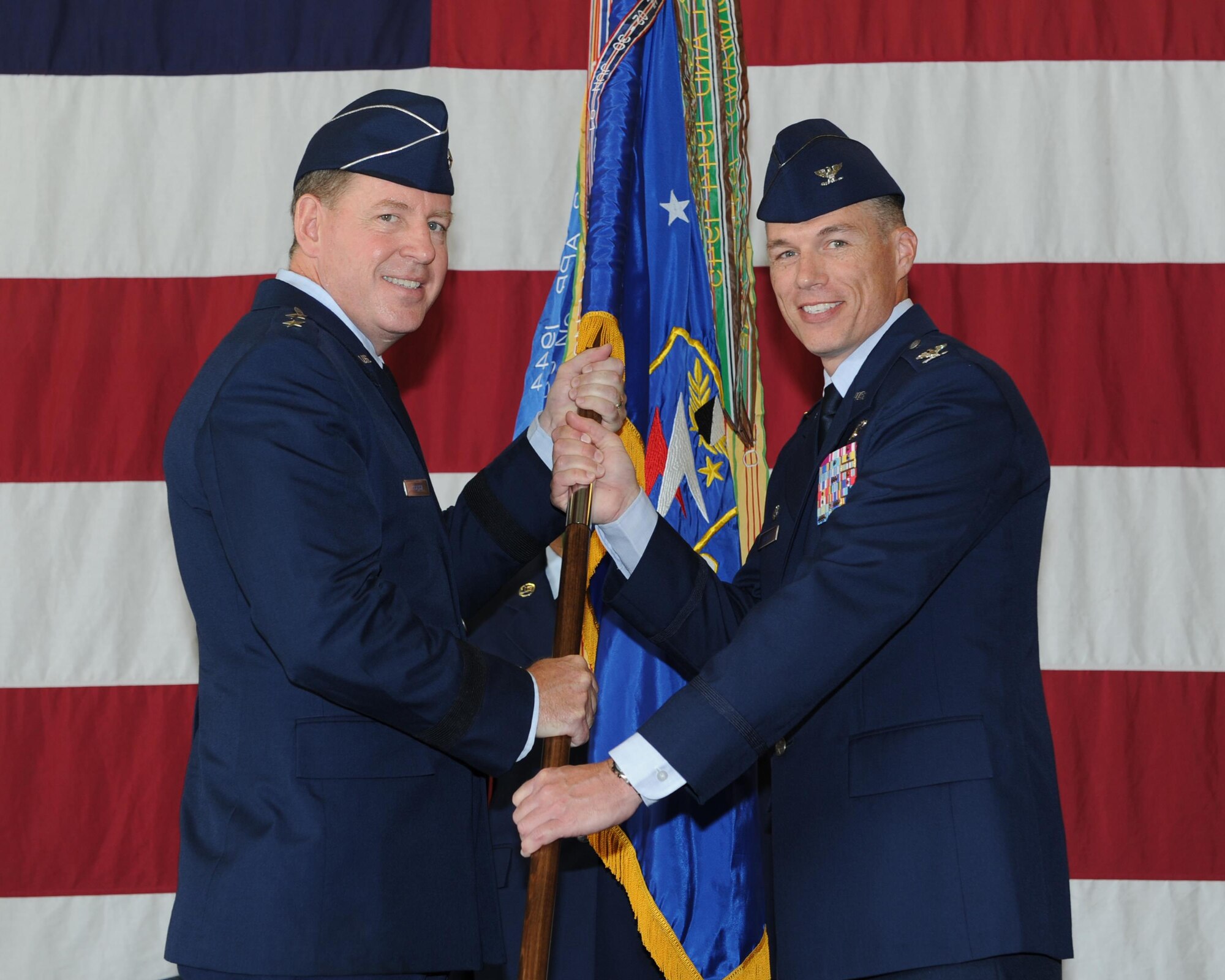 Maj. Gen. James Hecker, 19th Air Force Commander, Joint Base San Antonio–Randolph, Texas, passes the 14th Flying Training Wing guidon to Col. Douglas Gosney, the new 14th FTW Commander, during a change of command ceremony July 22 in the McAllister Fire Station at Columbus Air Force Base, Mississippi. (U.S. Air Force photo/Elizabeth Owens)