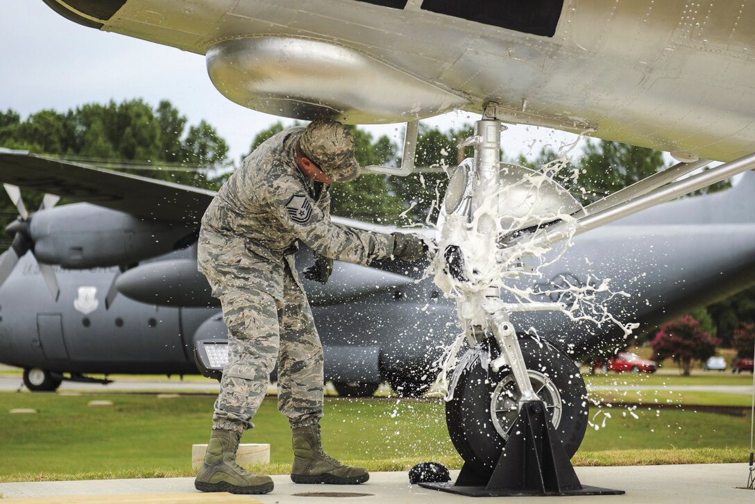 Master Sgt. Matthew Tabor breaks a bottle to christen an H-21B helicopter in Heritage Park at Little Rock Air Force Base, Ark., July 14, 2016. Air Force photo by Senior Airman Harry Brexel