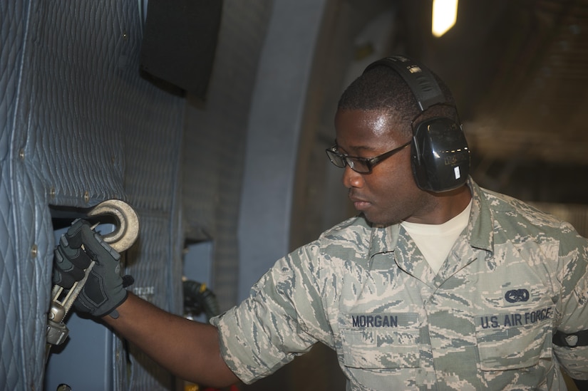 Kebar L. Morgan, a ramp loader with the 38th Aerial Port Squadron, grabs a hook for a tie-down off the wall of a C-5 Super Galaxy at Joint Base McGuire-Dix-Lakehurst, N.J., July 21, 2016. Morgan and other members of the 38th APS assisted the 305th APS with the transporting and loading of 50 Humvees to Iraq. 