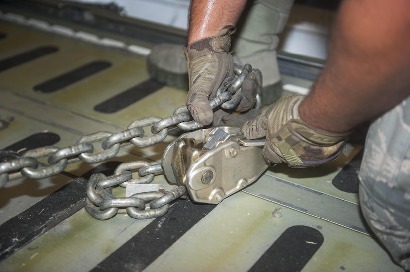 A 305th Port Dawg tightens the cargo tow chains securing a Humvee in a C-5 Super Galaxy at Joint Base McGuire-Dix-Lakehurst, N.J., July 21, 2016. The 305th Aerial Port Squadron handled and facilitated the transportation of 50 Humvees to Iraq in support of Operation Inherent Resolve. 