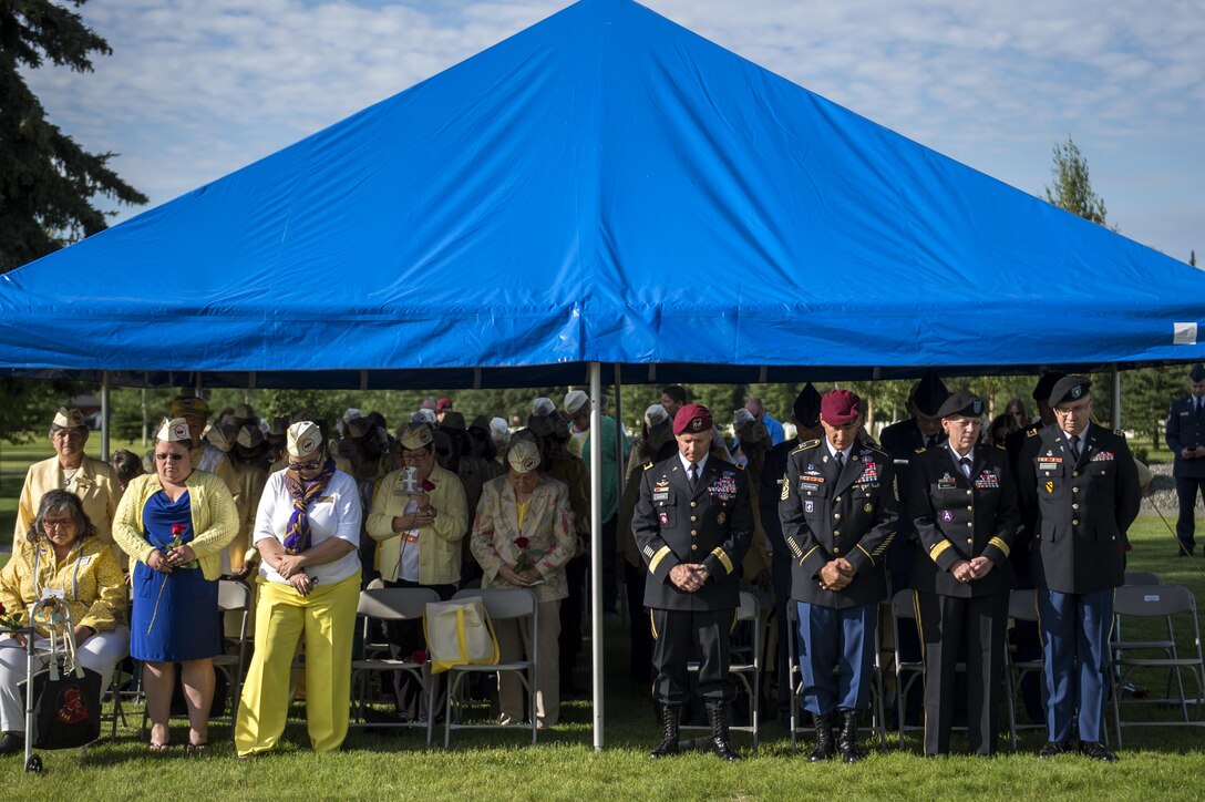 Leadership from Joint Base Elmendorf-Richardson bow their heads in prayer with Gold Star Wives during a memorial ceremony at the Fort Richardson National Cemetery, July 15, 2016 on Joint Base Elmendorf-Richardson, Alaska.  The memorial ceremony was a part of the Gold Star Wives of America's 71st National Convention hosted this year in Anchorage, Alaska.