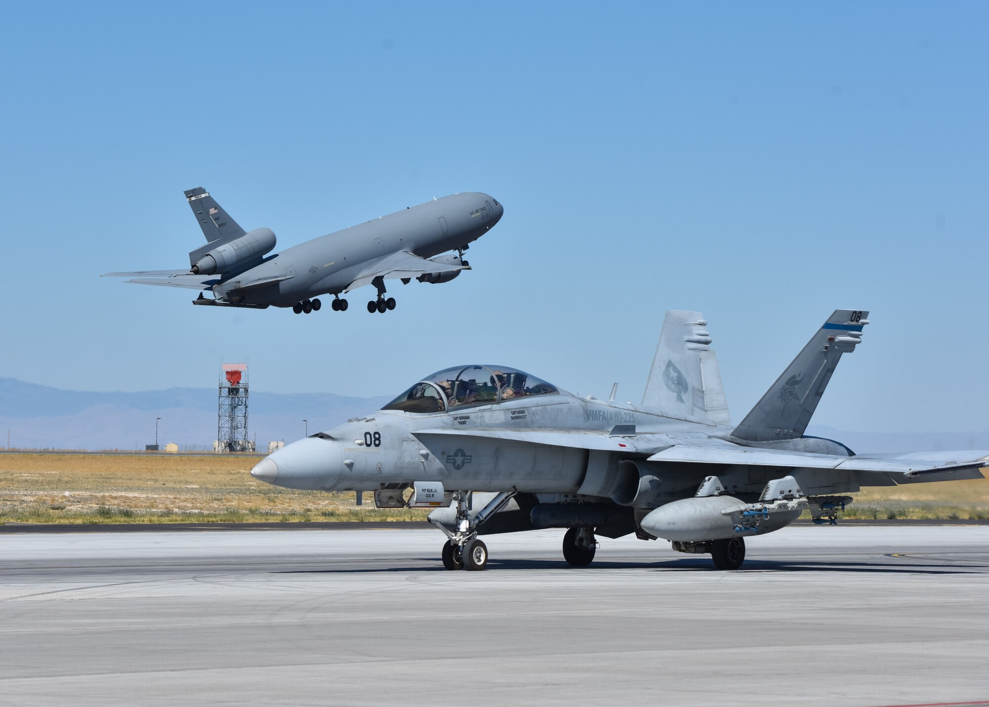 A KC-10 Extender from Travis Air Force Base, California takes off behind an F/A-18 Hornet from Marine Corps Air Station Miramar, California at Mountain Home Air Force Base, Idaho, July 20, 2016. The aircraft participated in multi-national exercise Gunfighter Flag 16-3 held at the Saylor Creek Training Range. (U.S. Air Force photo by Senior Airman Connor J. Marth/RELEASED)