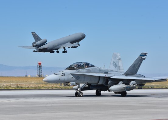 A KC-10 Extender from Travis Air Force Base, California takes off behind an F/A-18 Hornet from Marine Corps Air Station Miramar, California at Mountain Home Air Force Base, Idaho, July 20, 2016. The aircraft participated in multi-national exercise Gunfighter Flag 16-3 held at the Saylor Creek Training Range. (U.S. Air Force photo by Senior Airman Connor J. Marth/RELEASED)