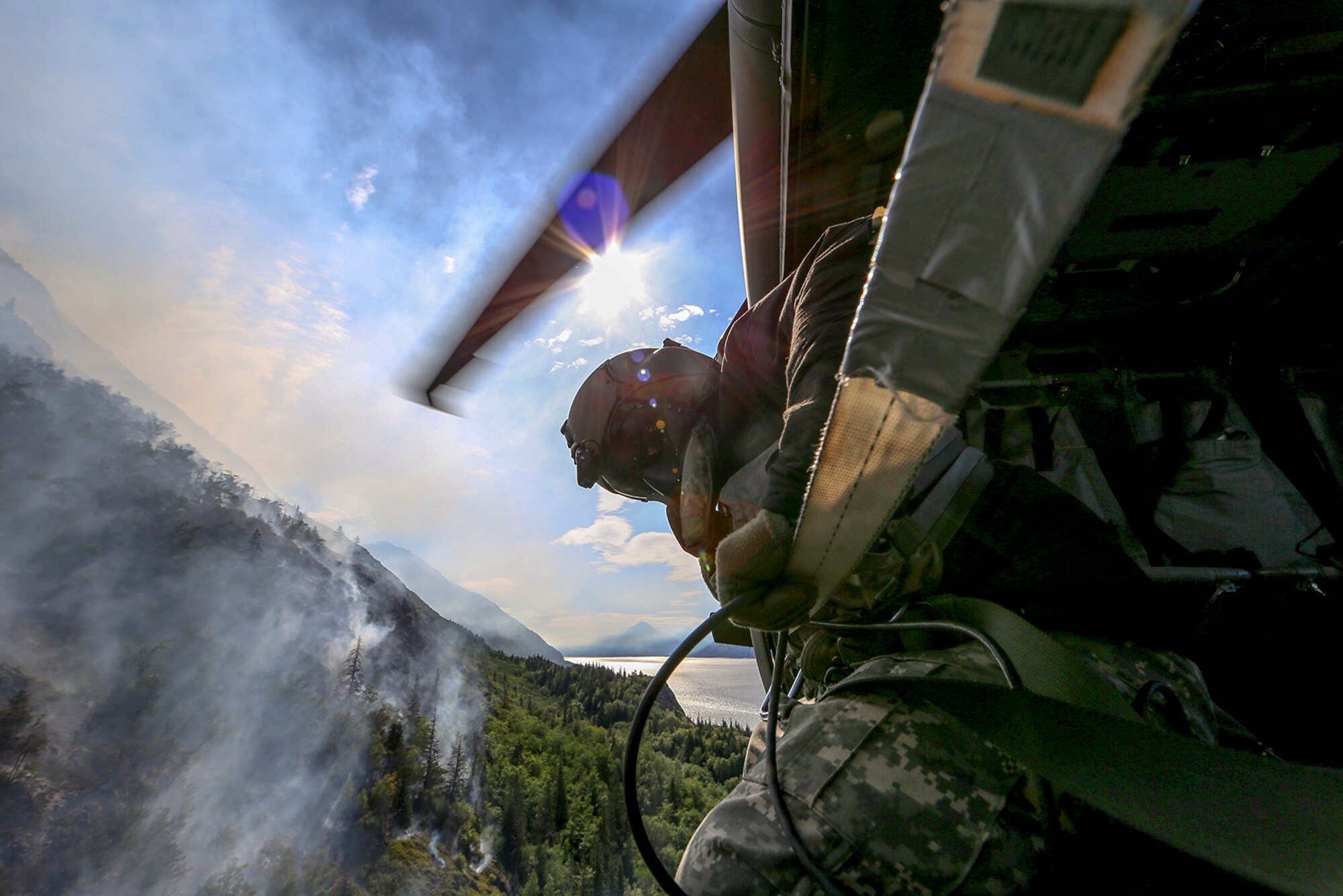 Staff Sgt. Steven Elliot, a crew chief with B Co., 1st Battalion, 207th Aviation Regiment, looks onto the McHugh Creek Fire during operations in support of wildfire suppression efforts near Anchorage, July 20, 2016. 