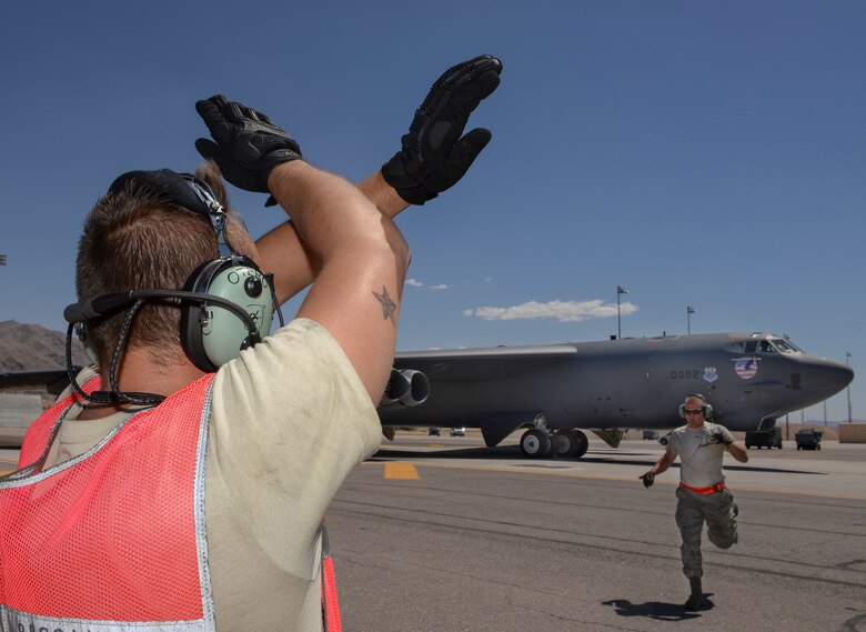 Senior Airman Joshua Otero, 96th Bomb Squadron crew chief, Barksdale Air Force Base, La., signals to a B-52 Stratofortress as Senior Airman Elias Sapp, 96th BS crew chief, runs to place before takeoff during Red Flag 16-3 at Nellis Air Force Base, Nev., July 18, 2016. Throughout Red Flag, crew chiefs launch aircraft in day and night operations providing various training scenarios that may differ from their home station. (U.S. Air Force photo by Senior Airman Kristin High/Released)