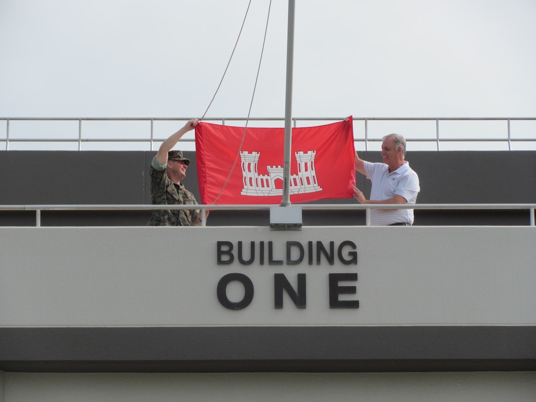 Passersby Marine Corps Air Station Iwakuni Building One on July 16 may have had to look twice when they saw the U.S. Army Corps of Engineer's bright red castle flag flying over the Marine headquarters.

Marine Col. Robert Boucher, commanding officer, MCAS Iwakuni, raised the USACE flag over the headquarters building with Lee Seeba, former resident engineer, Iwakuni Resident Office, under the joyful eyes of several Iwakuni Resident Office employees.

Boucher flew the engineer castle in Iwakuni as a "thank you" to the Corps' Iwakuni Resident Office for a job well done, after completing a particularly intricate project by deadline.

Bert Pechhold, current resident engineer, Iwakuni Resident Office, said the transformation that is occurring at MCAS Iwakuni could not be possible without the leadership and support from Boucher and his staff.

"This achievement symbolizes that spirit of cooperation and partnership between the Army and Marines," Pechhold said.

Seeba is currently the area engineer for the Japan District’s Okinawa Area Office.