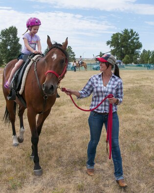 Aniya Welch, 6, daughter of Tech. Sgt. Chad Welch, 90th Civil Engineer Squadron Power Production NCO-in-charge, rides a horse led by volunteer, Senior Airman Samantha Vanvynck, 90th Operations Support Squadron Weather Flight, July 22, 2016, during Fort D.A. Russell Days, the annual F.E. Warren Air Force Base, Wyo., open house. The horse was provided by Horses 4 Heroes, a non-profit organization intending to boost morale with horse rides. (U.S. Air Force photo by Senior Airman Jason Wiese)