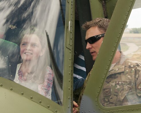 Staff Sgt. Travis Akerson, 37th Helicopter Squadron special mission aviator, discusses the mission of his squadron to Amelia Gallegos, 8, sitting in the cockpit of a UH-1N Bell Helicopter on display July 22, 2016, during Fort D.A. Russell Days, the annual F.E. Warren Air Force Base, Wyo., open house. The helicopter was used by the U.S. military in the Vietnam War, and is used today in nuclear deterrence operations. (U.S. Air Force photo by Senior Airman Jason Wiese)