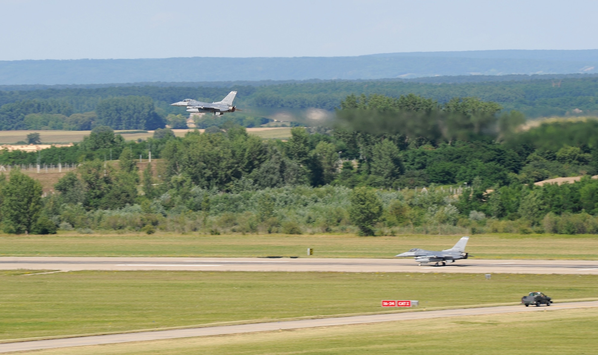 An F-16 Fighting Falcon aircraft from the 140th Wing, Colorado Air National Guard, makes a fly-by maneuver over a taxiing F-16 at Papa Air Base, Papa, Hungary after returning from a training mission in support of Operation Panther Strike. conjunction with Operation Atlantic Resolve, the 140th Wing, Colorado Air National Guard from Buckley Air Force Base, Colorado, has deployed approximately 200 Airmen to Papa Air Base, Hungary, to conduct familiarization training alongside our NATO ally, Hungary. They will also participate in cross-border training with other deployed U.S. forces' aircraft and NATO aircraft in the region. This deployment continues to demonstrate our commitment to our allies and European security and stability. (U.S. Air National Guard photo by Senior Master Sgt. John Rohrer) 