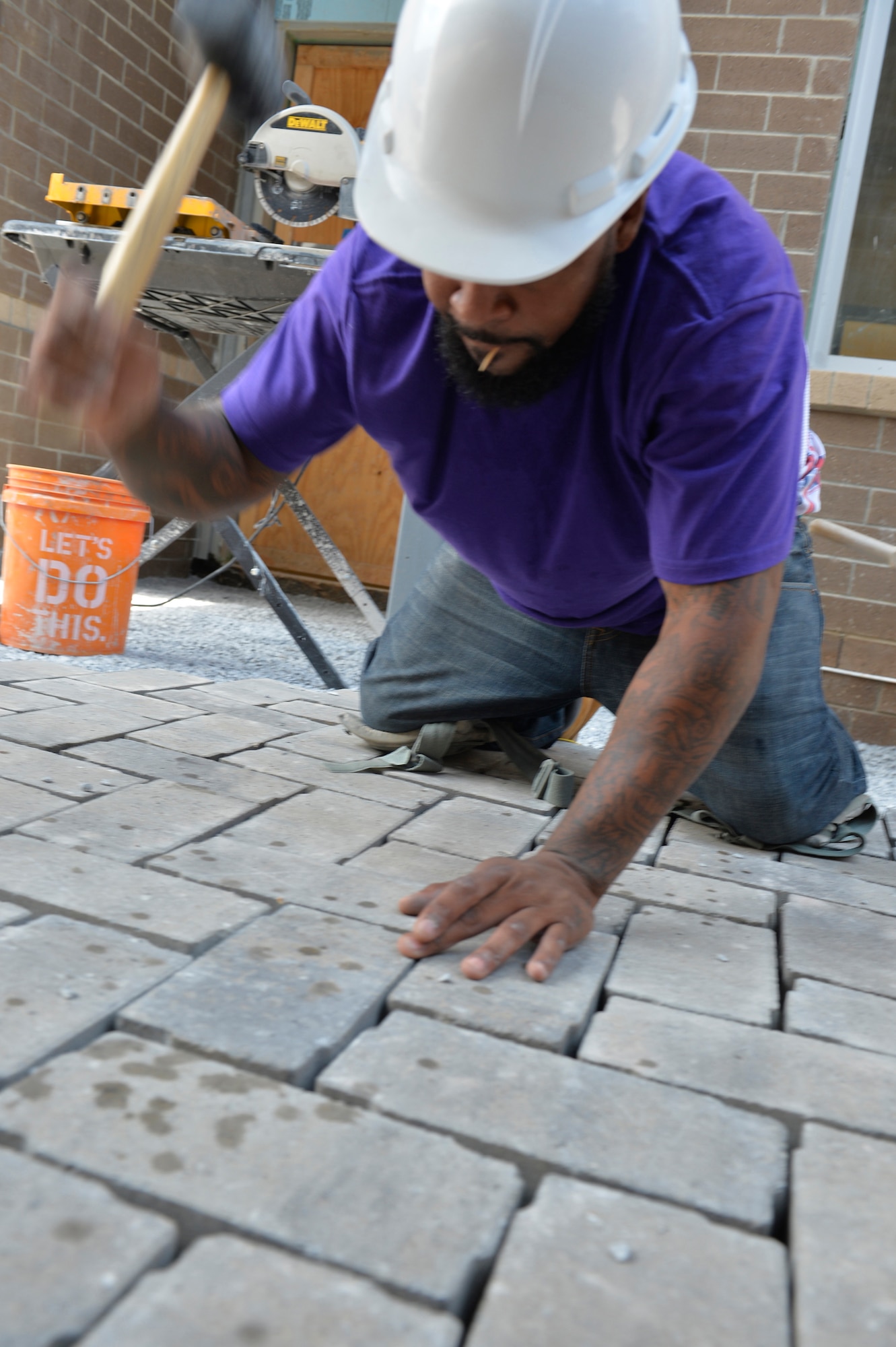 A brick mason pounds a paving brick in to place in the courtyard between the new dormitory buildings here, July 22, 2016, at the I.G. Brown Training and Education Center in Louisville, Tenn. (U.S. Air National Guard photo by Master Sgt. Jerry D. Harlan)