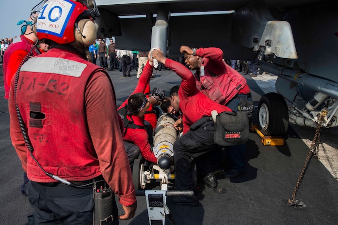 Aviation ordnancemen load ordnance to the wing of an F/A-18F Super Hornet assigned to the Fighting Swordsmen of Strike Fighter Squadron (VFA) 32 on the flight deck of the aircraft carrier USS Dwight D. Eisenhower (CVN 69). Dwight D. Eisenhower and its carrier strike group are deployed in support of Operation Inherent Resolve, maritime security operations and theater security cooperation efforts in the U.S. 5th Fleet area of operations.