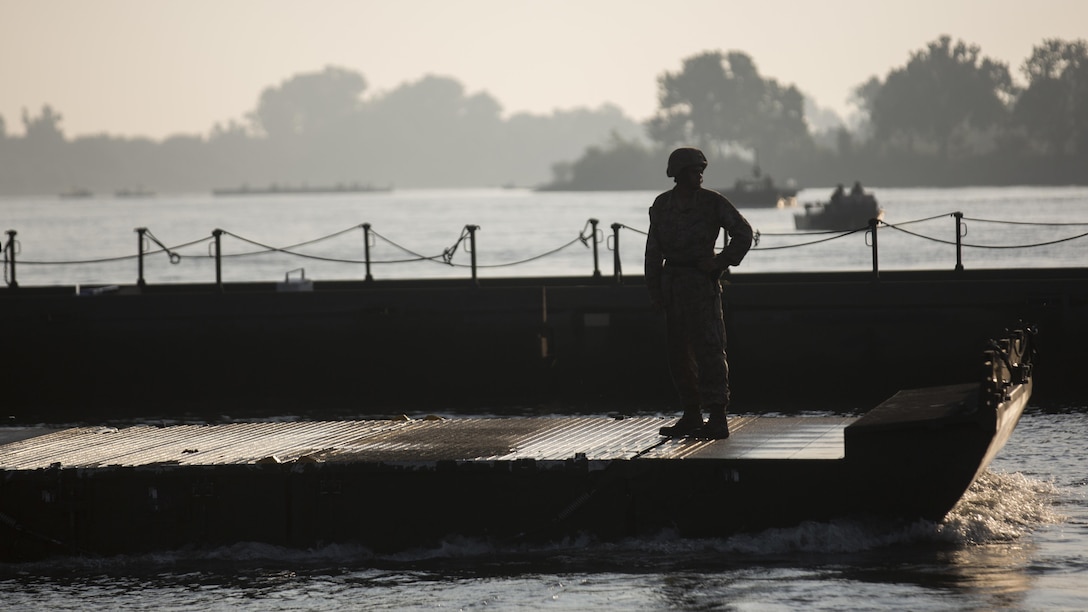 A Marine with Bridge Company, 8th Engineer Support Battalion guides an Improved Ribbon Bridge into place during Exercise River Assault on Fort Chaffee, Arkansas, July 19, 2016. The Marines prepped and guided IRBs upstream to where the 814th Multi-Roll Bridge Co. was constructing their portion of the continuous IRB.