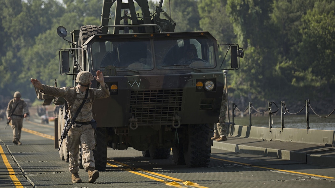 Lance Cpl. Thomas Devito, a boat operator with Bridge Company Bravo, 6th Engineer Support Company, guides an M977 heavy expanded mobility tactical truck across the continuous span bridge during Exercise River Assault on Fort Chaffee, Arkansas, July 19, 2016. The Marines spent two weeks operating Mk3 bridge erection boats, and practicing connecting all the IRBs in preparation for the final exercise, which was a continuous IRB span across the Arkansas River.