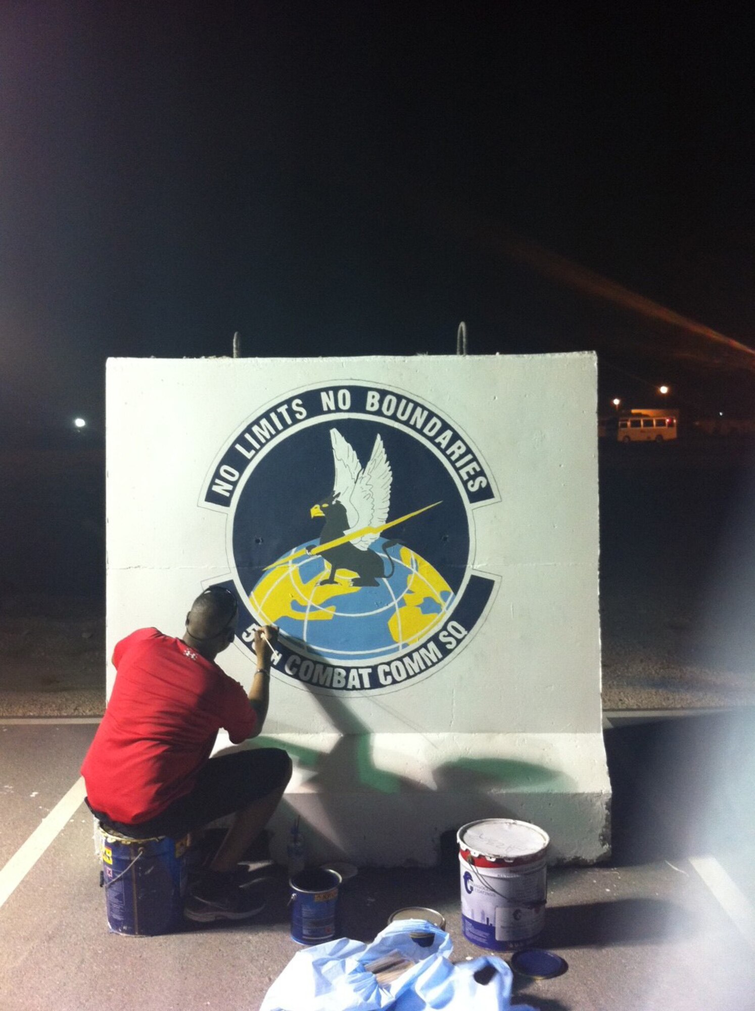 U.S. Air Force Reserve Master Sgt. Nichols Hermon, 55th Combat Communications Squadron, adding the finishing touches on the security barrier bearing the 55th CBCS emblem at an undisclosed deployed location in the Air Forces Central Command area of responsibility. Twelve Citizen Airmen  deployed recently and were afforded the opportunity to leave a lasting mark at the base to commemorate the work their time there. (U.S. Air Force courtesy photo) 
