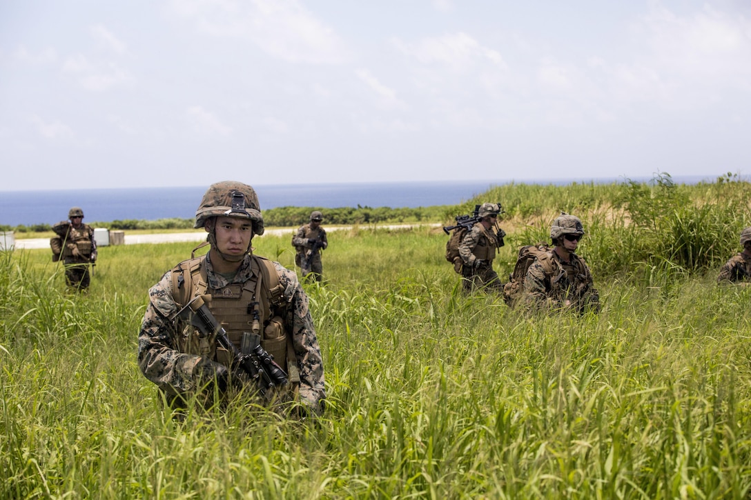 U.S. Marines hike to their designated position to set up security around an air strip July 20, 2016 2016 at Iejima, Okinawa, Japan. Marines immediately set up security, simulated engaging the enemy and set up a combat operations center after getting off an MV-22B Osprey Tiltrotor Aircraft. The Marines were a part of Golf Company, 2nd Marine Division currently attached to 4th Marine Regiment, 3rd Marine Division, III Marine Expeditionary Force through the unit deployment program. (U.S. Marine Corps photo by Lance Cpl. Amaia Unanue/Released)