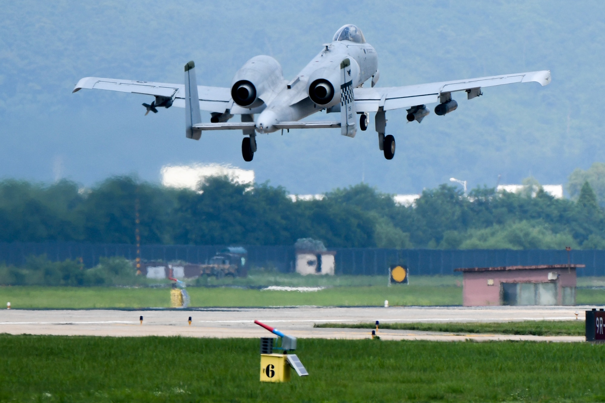 An A-10 Thunderbolt II flies over a bird and wildlife aircraft strike hazard cannon placed on the flightline at Osan Air Base, Republic of Korea, July 19, 2016. The cannons, operated by the 51st Fighter Wing safety office, can make a variety of noises from large booms to wild animal distress noises to help detour Korea’s wildlife from the flightline. This ensures the safety of both the wildlife and pilots operating aircraft. (U.S. Air Force photo by Staff Sgt. Jonathan Steffen/Released)