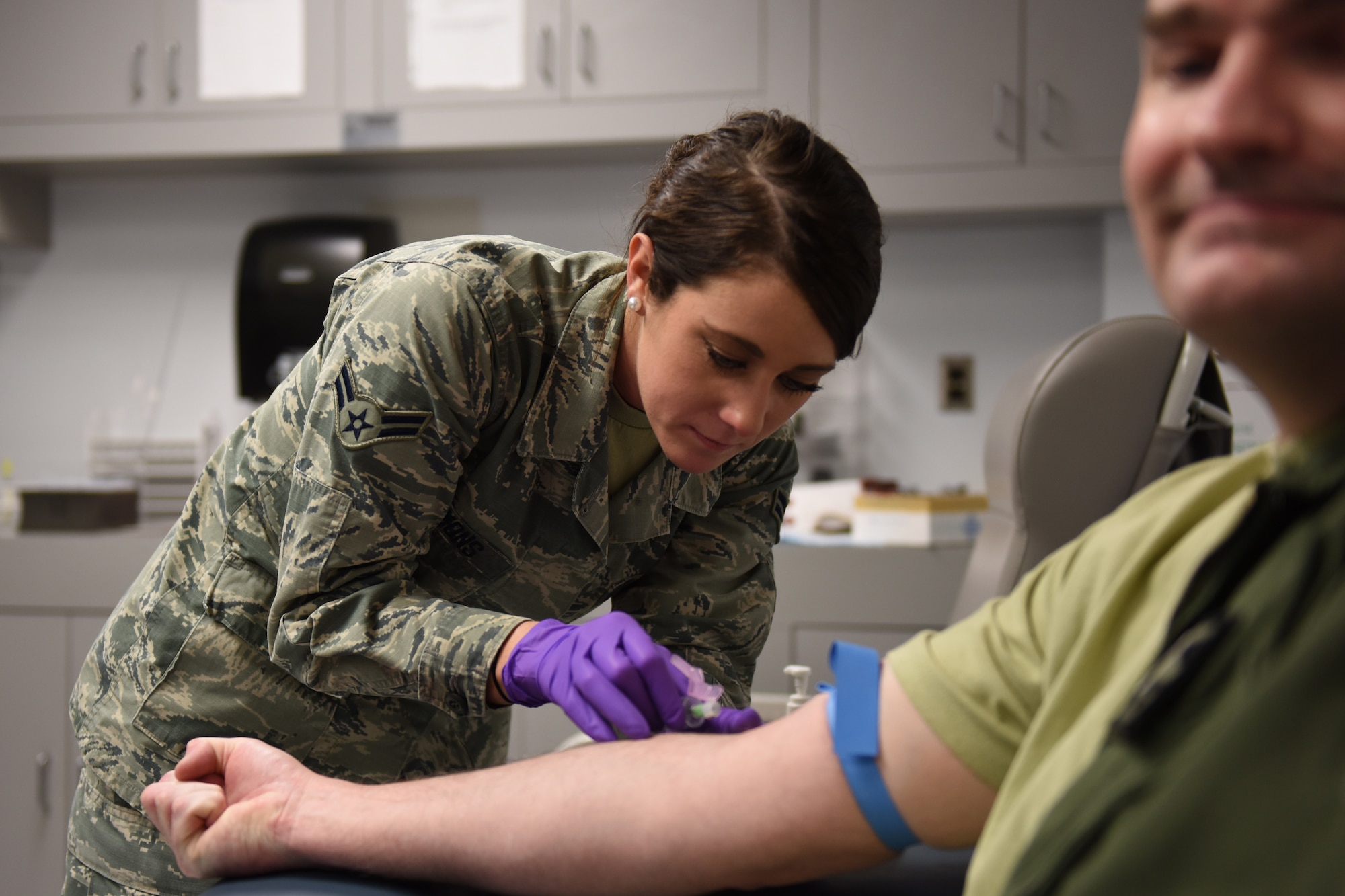 Airman 1st Class Kelsey Symons (left), 193rd Special Operations Wing Medical Group aerospace medical technician, draws a blood sample from an Airman during his regular medical examination on base at Middletown, Pennsylvania. The wing’s flying mission annually requires more than 250 flight physicals and more than 800 occupational health exams to be conducted by the group. (U.S. Air National Guard photo by Senior Airman Ethan Carl/Released)