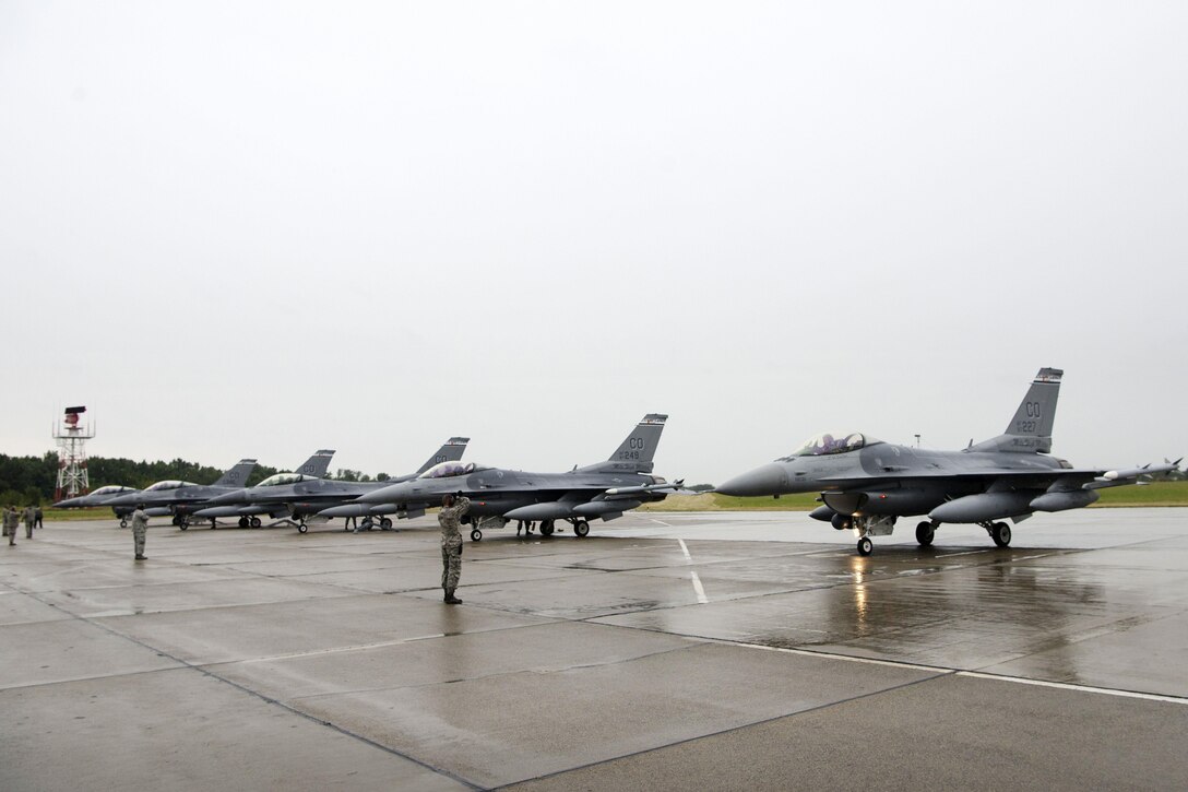 Air Force airmen prepare five F-16 Fighting Falcon aircraft for a rainy-day flight mission at Papa Air Base, Hungary, July 16, 2016. The pilots and crews are assigned to the Colorado Air National Guard’s 140th Wing. This is the first time Colorado jets have landed in Hungary. The F-16s will be supporting Operation Atlantic Resolve, and the airmen of the 140th Wing will also be conducting familiarization training alongside Hungary, a NATO ally. Air National Guard photo by Senior Master Sgt. John Rohrer