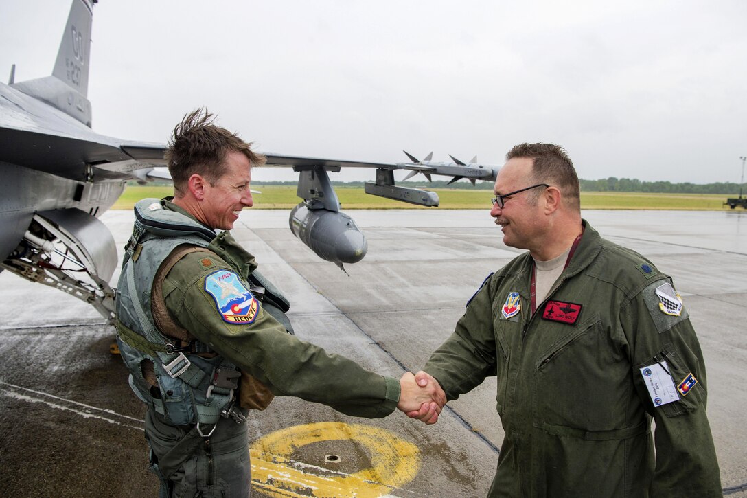 Air Force Maj. Joshua L. Burger, left, greets Air Force Lt. Col. Craig A. Wolf upon landing his F-16 Fighting Falcon aircraft in the rain at Papa Air Base, Hungary, July 16, 2016. Burger is a pilot assigned to the Colorado Air National Guard’s 140th Wing. Air National Guard photo by Senior Master Sgt. John Rohrer