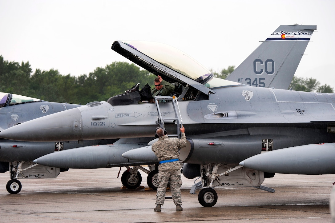Air Force Master Sgt. John A. Saint George, foreground, sets a ladder for Air Force Capt. James H. Edwards as he prepares to exit his F-16 Fighting Falcon aircraft after landing at Papa Air Base, Hungary, July 16, 2016. Saint George is a crew chief and Edwards is a pilot assigned to the Colorado Air National Guard’s 140th Wing. Air National Guard photo by Senior Master Sgt. John Rohrer