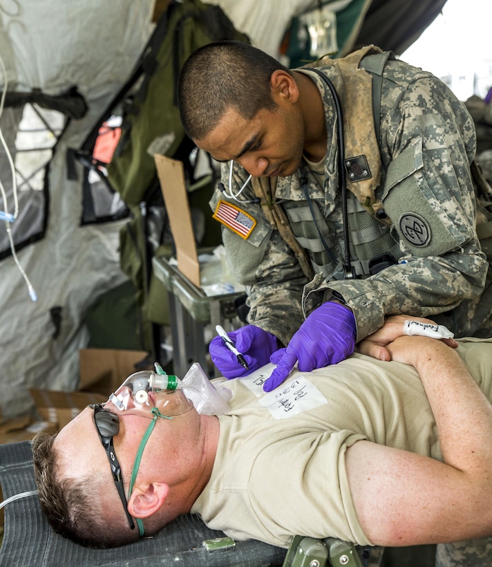 Army Spc. Muhammad Alam, right, marks a soldier for triage during a mass casualty exercise at the Joint Readiness Training Center, Fort Polk, La., July 16, 2016. Alam is assigned to the New York Army National Guard's Headquarters Company, 1st Battalion 69th Infantry. Army National Guard photo by Sgt. Harley Jelis