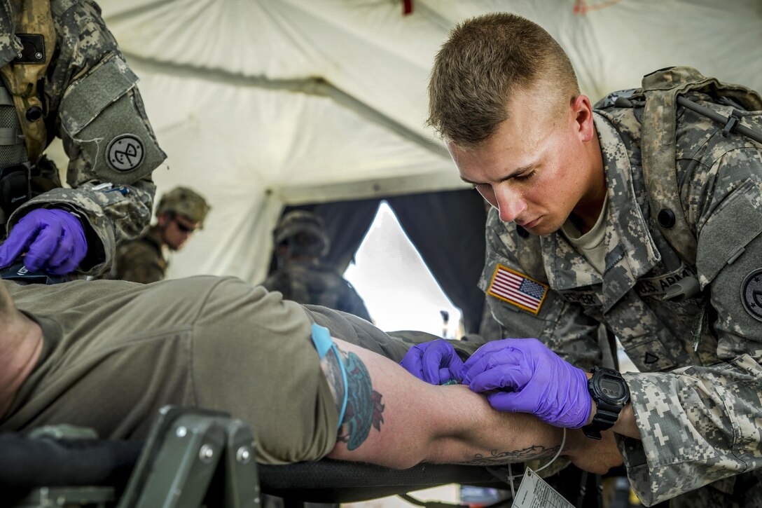 Army Pfc. Beau Fisher administers fluids to a simulated casualty during a mass casualty exercise at the Joint Readiness Training Center, Fort Polk, La., July 16, 2016. Fisher is assigned to the New York Army National Guard's Headquarters Company, 1st Battalion 69th Infantry. Army National Guard photo by Sgt. Harley Jelis