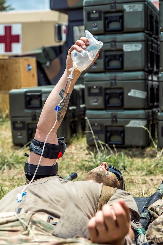 A soldier posing as a casualty holds his IV fluid bag during a mass casualty exercise at the Joint Readiness Training Center, Fort Polk, La., July 16, 2016. The soldier is assigned to the Massachusetts Army National Guard's 1st Battalion, 182nd Infantry. Army National Guard photo by Sgt. Harley Jelis