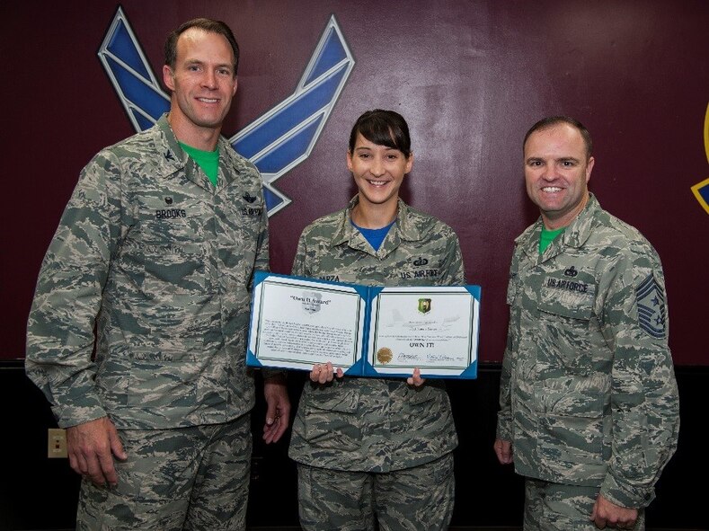 Tech. Sgt. Janene Garza, 5th Comptroller Squadron budget analyst, receives the “Own It” award from Col. Matthew Brooks, 5th Bomb Wing commander, and Chief Master Sgt. Paul Elliot, 5 BW command chief, at Minot Air Force Base, N.D., July 22, 2016. Garza received the award for managing the 5th Medical Group’s $9.3 million budget among other things. (U.S. Air Force photo/Airman 1st Class Christian Sullivan)