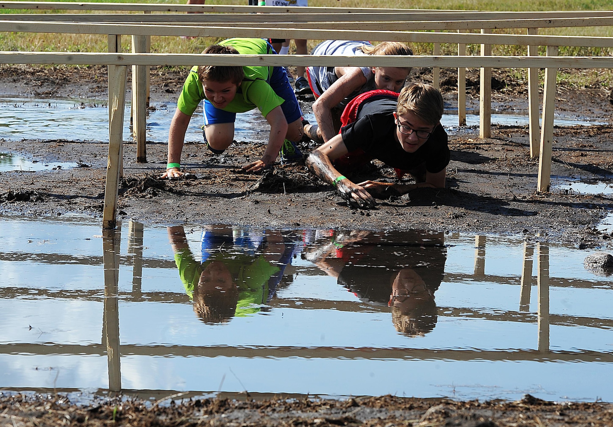 Minot AFB youth crawl through an obstacle during the 2016 Mini Mudder, July 15, 2016 at Minot Air Force Base, N.D. The race consisted of different obstacles that challenged Airmen and their families to crawl, climb, run and slide through mud and water. (U.S. Air Force photo/Senior Airman Kristoffer Kaubisch)
