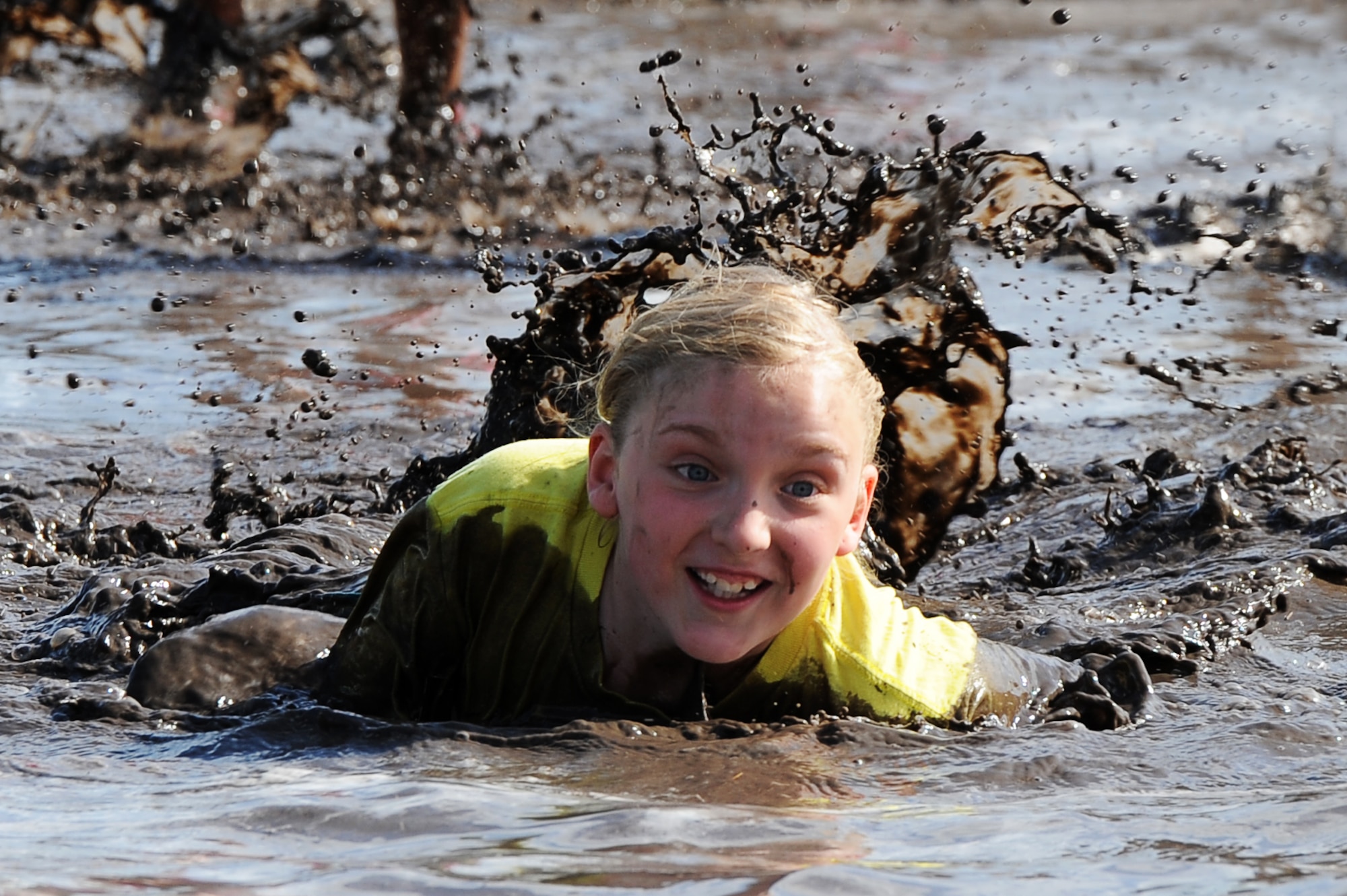 A military crawls through the mud during the 2016 Mini Mudder, July 15, 2016 at Minot Air Force Base, N.D. The race consisted of different obstacles that challenged Airmen and their families to crawl, climb, run and slide through mud and water. (U.S. Air Force photo/Senior Airman Kristoffer Kaubisch)